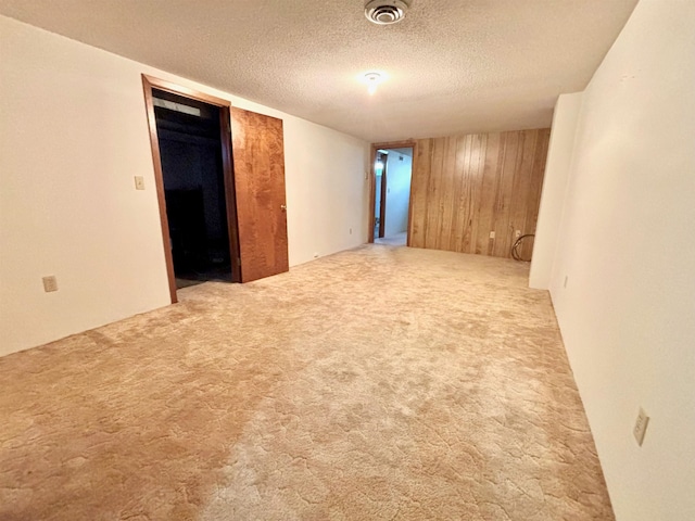 empty room featuring wood walls, a textured ceiling, and carpet