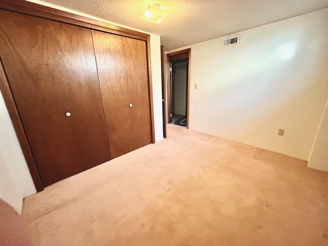 unfurnished bedroom featuring carpet floors, a textured ceiling, and a closet