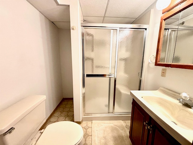 bathroom featuring a drop ceiling, an enclosed shower, vanity, and toilet