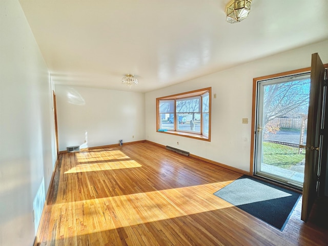 interior space with a wealth of natural light, a notable chandelier, and hardwood / wood-style flooring