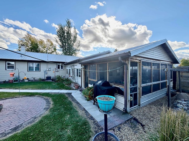 rear view of house featuring a sunroom and a yard