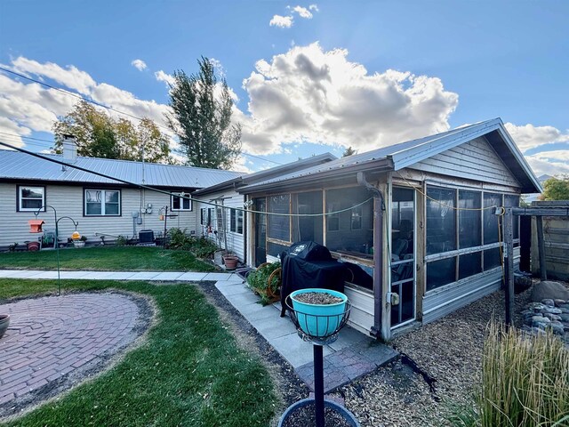 6 4th Ave, Towner, ND 58788 - rear view of property with a sunroom, a yard, metal roof, and a patio area