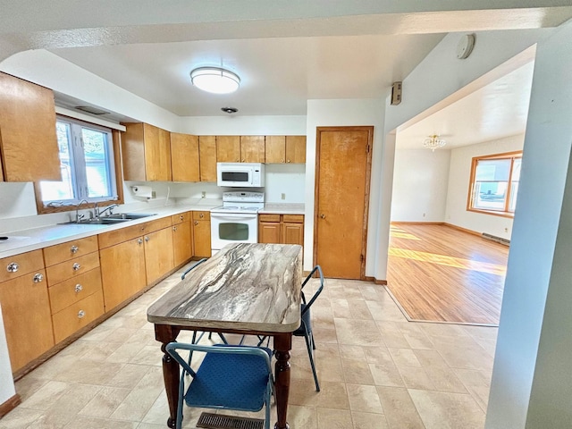 6 4th Ave, Towner, ND 58788 - kitchen featuring white appliances, a sink, light countertops, baseboards, and brown cabinets