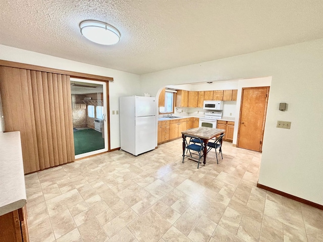 kitchen with a textured ceiling, white appliances, and sink