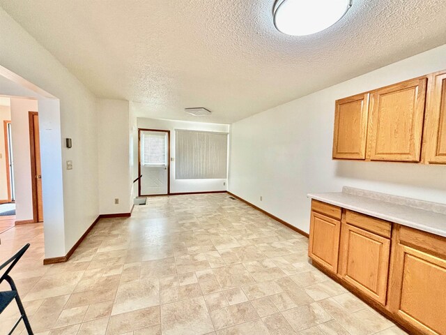 6 4th Ave, Towner, ND 58788 - kitchen with a textured ceiling, baseboards, light countertops, and brown cabinetry