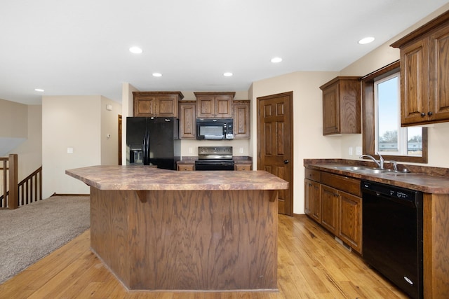 kitchen featuring light wood-type flooring, sink, black appliances, and a kitchen island