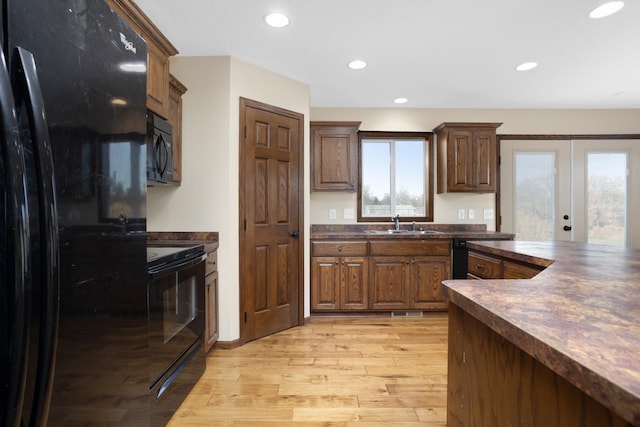 kitchen featuring black appliances, sink, light hardwood / wood-style floors, and french doors