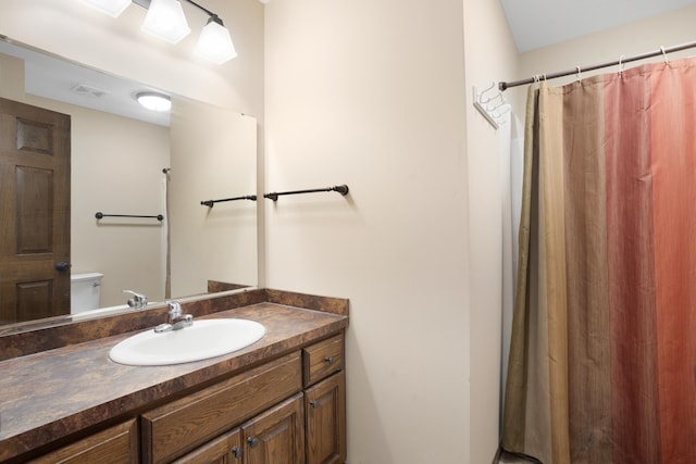 bathroom with a shower with shower curtain, vanity, and toilet