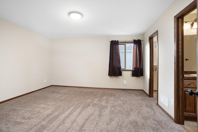 unfurnished bedroom featuring light colored carpet and connected bathroom