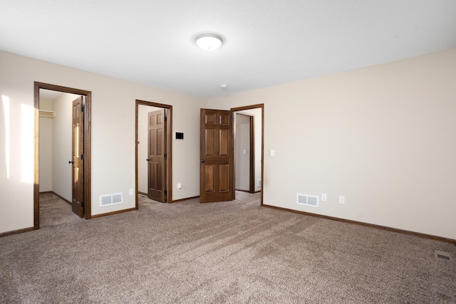 unfurnished bedroom with a walk in closet and carpet floors