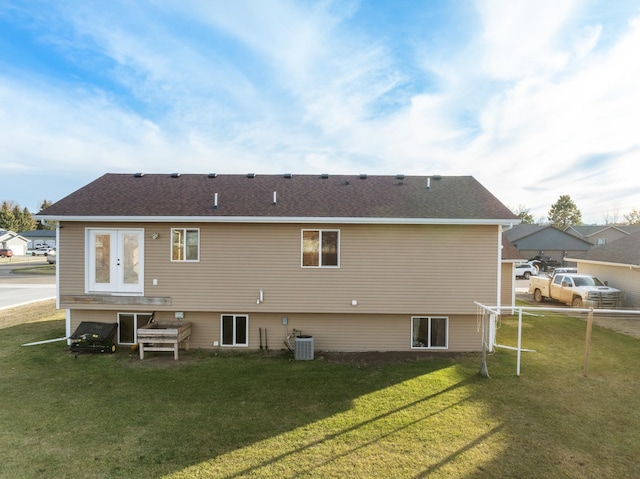 rear view of house with cooling unit and a lawn