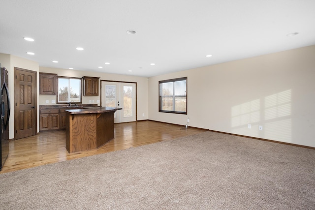 kitchen with a kitchen island, light wood-type flooring, sink, and a kitchen breakfast bar