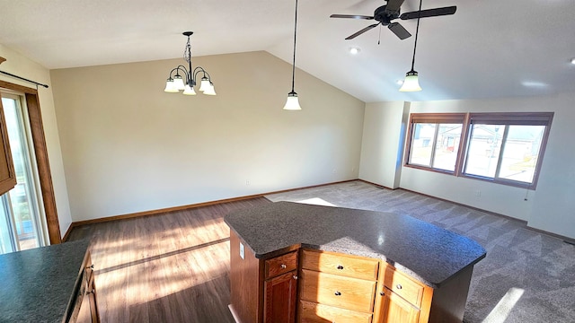 kitchen with hardwood / wood-style floors, ceiling fan with notable chandelier, hanging light fixtures, and vaulted ceiling