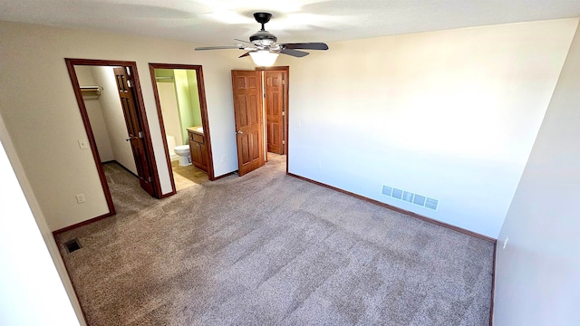 unfurnished bedroom with connected bathroom, ceiling fan, a walk in closet, light carpet, and a closet