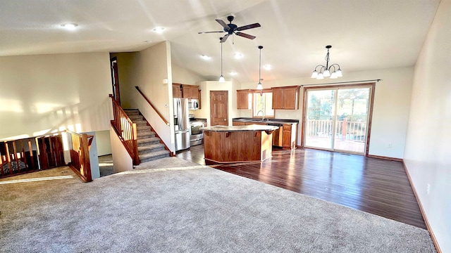 kitchen featuring ceiling fan with notable chandelier, dark hardwood / wood-style floors, decorative light fixtures, a kitchen island, and stainless steel appliances