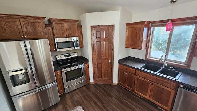 kitchen with dark hardwood / wood-style flooring, stainless steel appliances, vaulted ceiling, sink, and pendant lighting