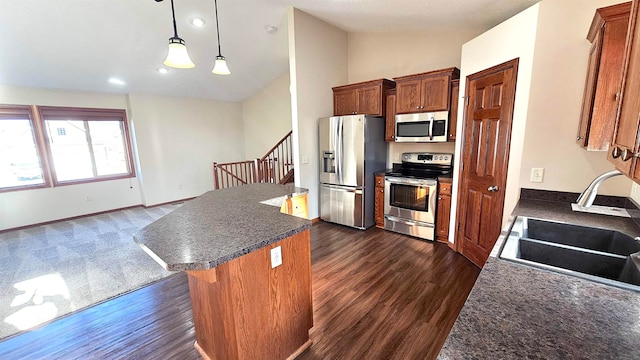 kitchen with appliances with stainless steel finishes, sink, a center island, hanging light fixtures, and lofted ceiling