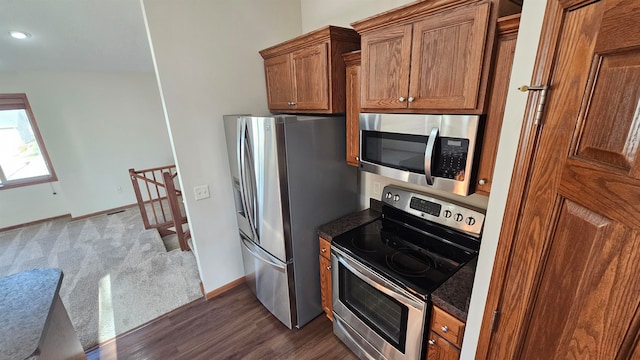 kitchen with dark stone counters, stainless steel appliances, and dark hardwood / wood-style floors