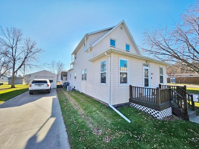 view of property exterior featuring a yard, a garage, an outdoor structure, and a wooden deck