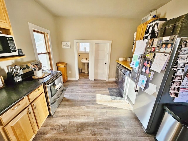 kitchen with sink, washer / clothes dryer, light hardwood / wood-style floors, stainless steel range with electric stovetop, and light brown cabinetry