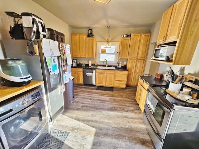 kitchen featuring sink, hardwood / wood-style flooring, decorative light fixtures, washer / dryer, and stainless steel appliances