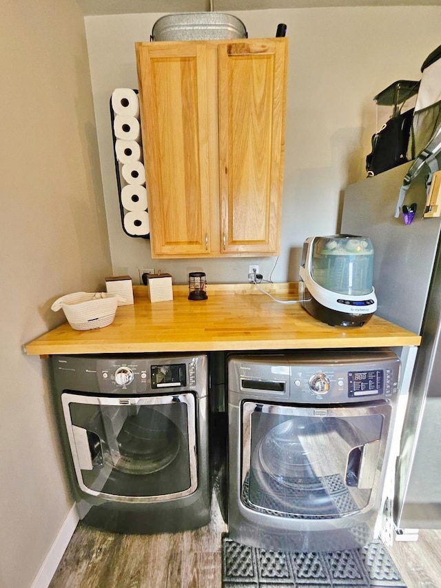 laundry room with cabinets, wood-type flooring, and separate washer and dryer