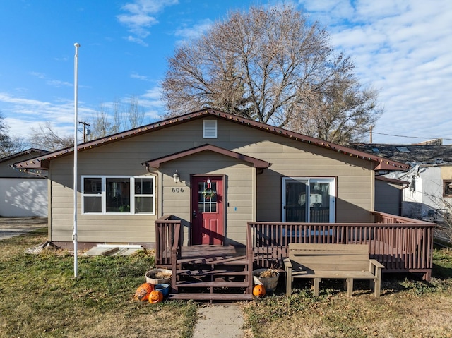 view of front facade with a wooden deck and a front yard