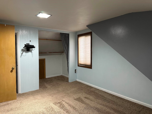 interior space featuring a closet, light colored carpet, and vaulted ceiling