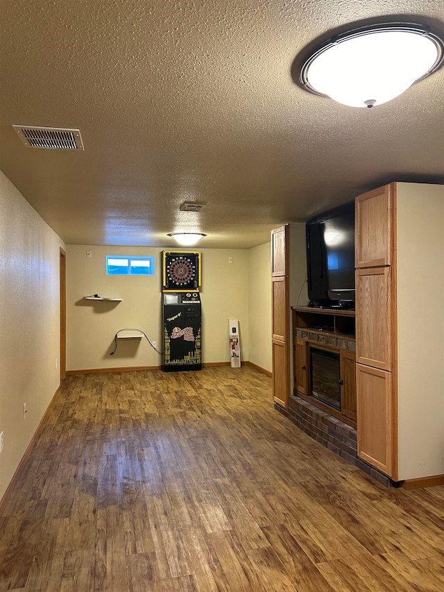 unfurnished living room with a textured ceiling, dark wood-type flooring, and a brick fireplace