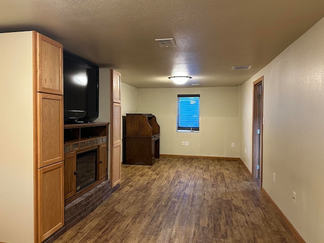 unfurnished living room featuring a textured ceiling and dark hardwood / wood-style flooring