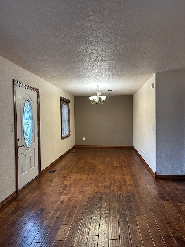 foyer with a textured ceiling, dark wood-type flooring, and a notable chandelier