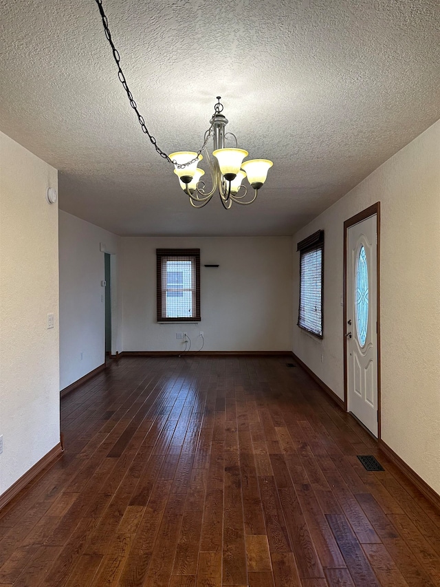 interior space with dark hardwood / wood-style flooring, a chandelier, and a textured ceiling