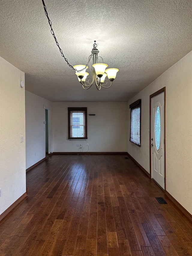 interior space with a chandelier, dark wood-type flooring, and a textured ceiling