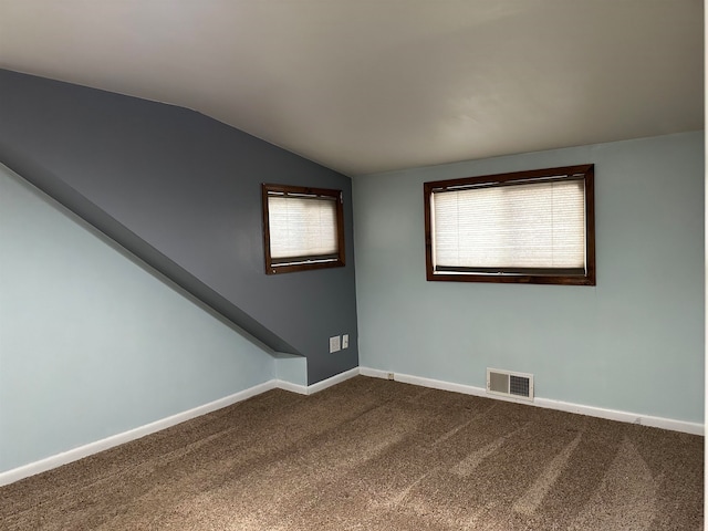 carpeted spare room featuring a wealth of natural light and vaulted ceiling