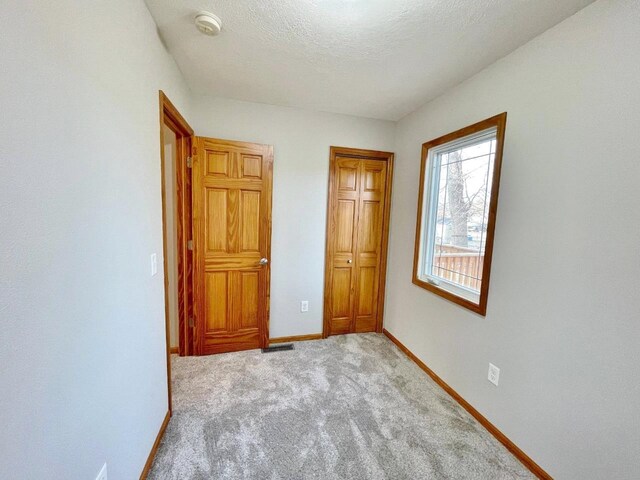 unfurnished bedroom featuring a textured ceiling and light colored carpet