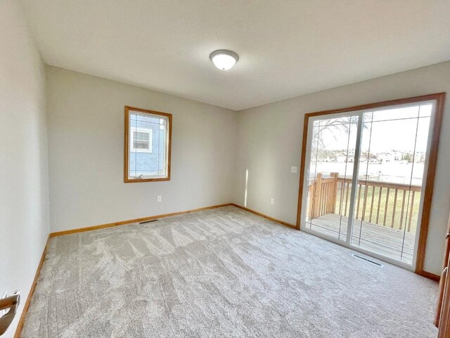 unfurnished room with light carpet, a textured ceiling, and plenty of natural light