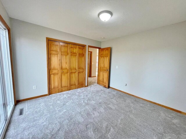 unfurnished bedroom featuring carpet, a textured ceiling, and a closet