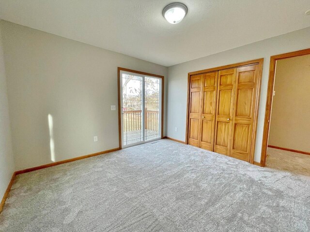 unfurnished bedroom featuring carpet flooring, a closet, a textured ceiling, and access to outside