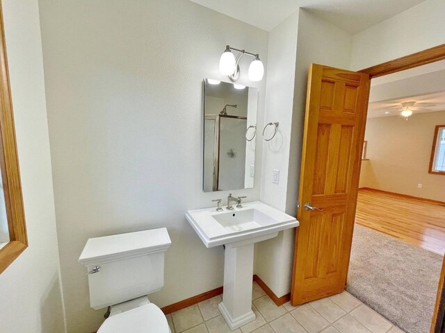 bathroom featuring tile patterned flooring, a shower with door, and toilet