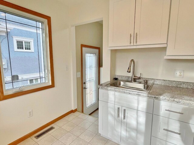 kitchen featuring white cabinets, light tile patterned floors, and sink