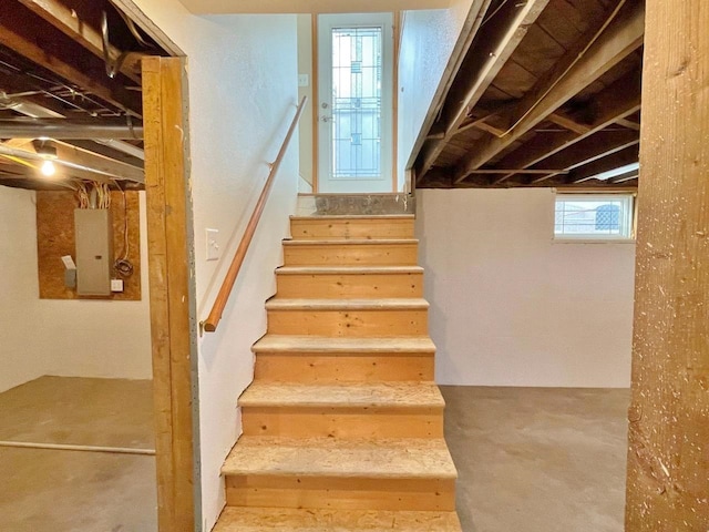 staircase featuring concrete floors and electric panel