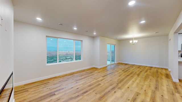 spare room featuring an inviting chandelier and light hardwood / wood-style flooring