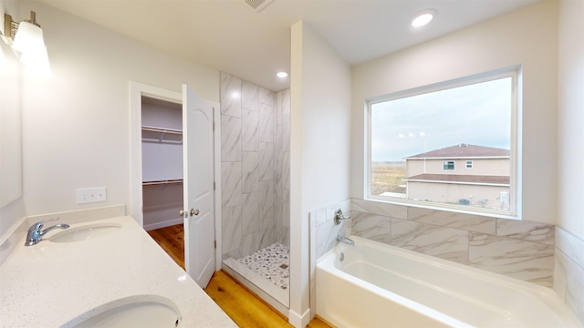 bathroom featuring hardwood / wood-style flooring, vanity, and plus walk in shower