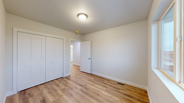 unfurnished bedroom with a closet and light hardwood / wood-style flooring