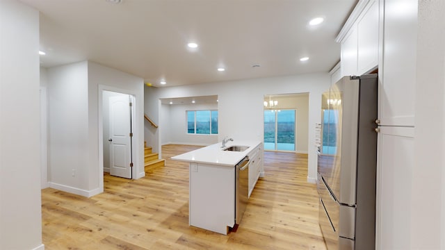 kitchen with a center island with sink, white cabinets, light wood-type flooring, and stainless steel appliances