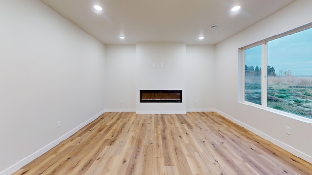 unfurnished living room featuring light wood-type flooring and a wealth of natural light