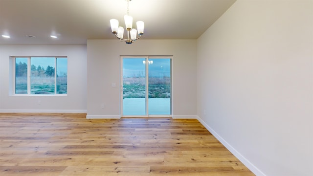 empty room featuring light hardwood / wood-style floors and a notable chandelier