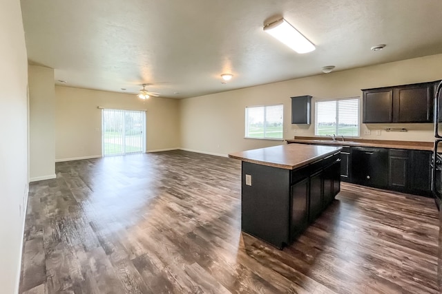 kitchen with ceiling fan, a center island, sink, black dishwasher, and dark hardwood / wood-style flooring