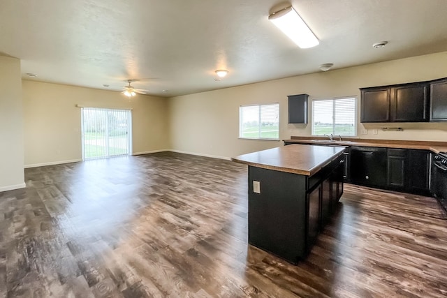 kitchen featuring dishwasher, dark wood-type flooring, sink, ceiling fan, and a kitchen island