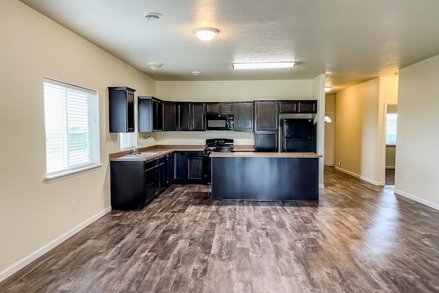 kitchen with sink, a kitchen island, black appliances, and dark hardwood / wood-style floors